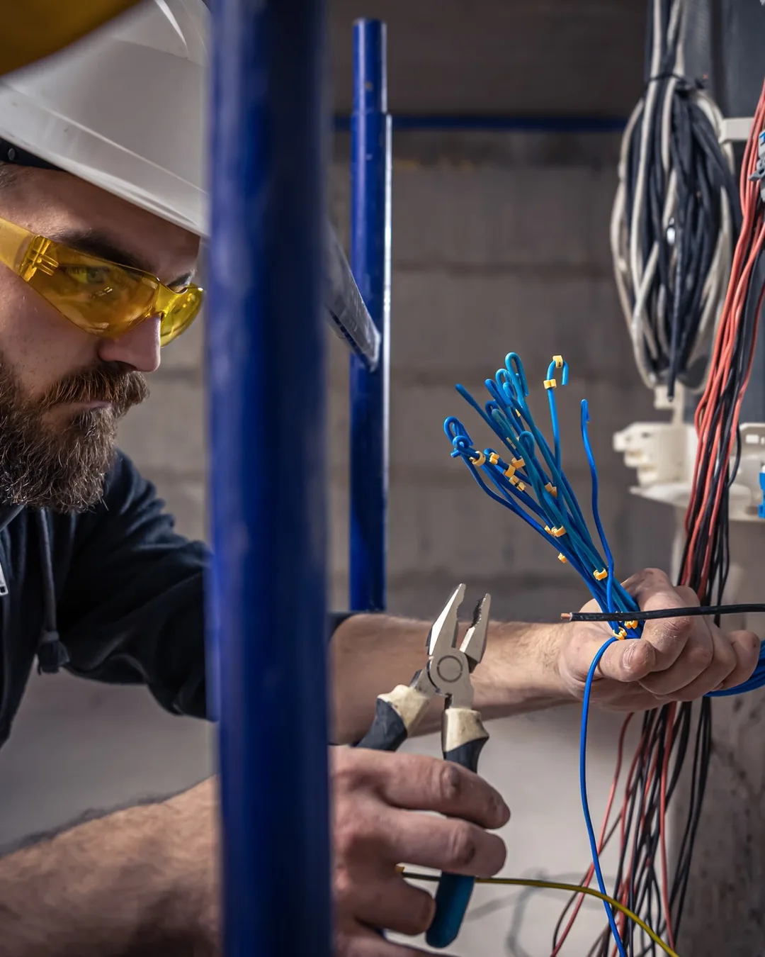 Elektryk podłącza przewody w rozdzielnicy elektrycznej